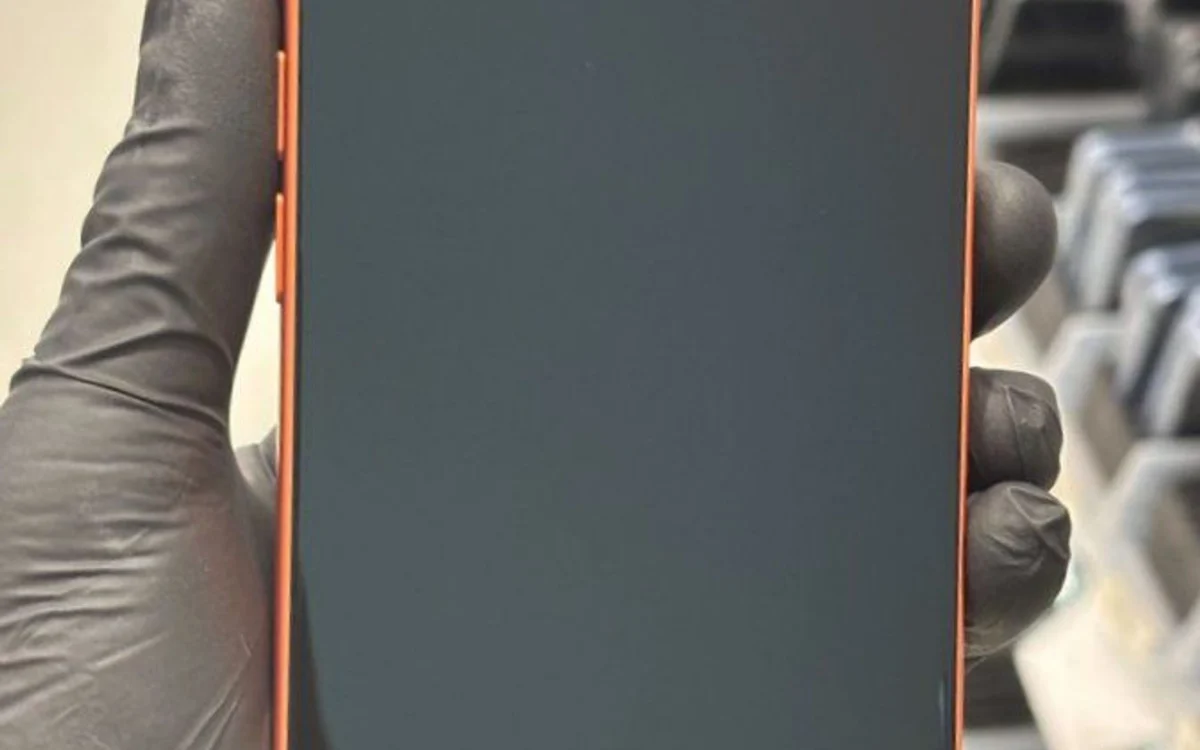 Un technicien ganté contrôle l'écran d'un téléphone